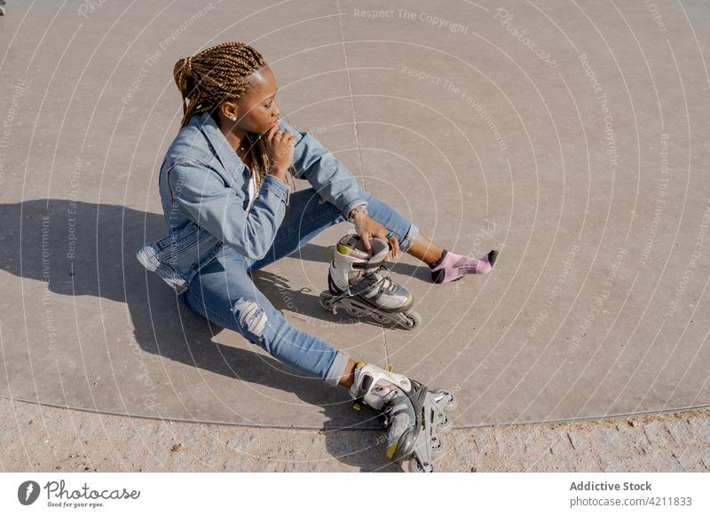 Black woman in rollerblades in skate park summer put on enjoy hobby sunny female ethnic black african american style denim cool prepare carefree urban jeans