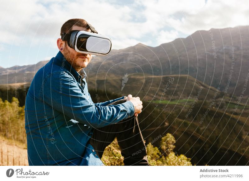 Traveling man using VR glasses in mountains traveler virtual reality experience vr highland goggles male adventure enjoy hill explore trip nature sit device