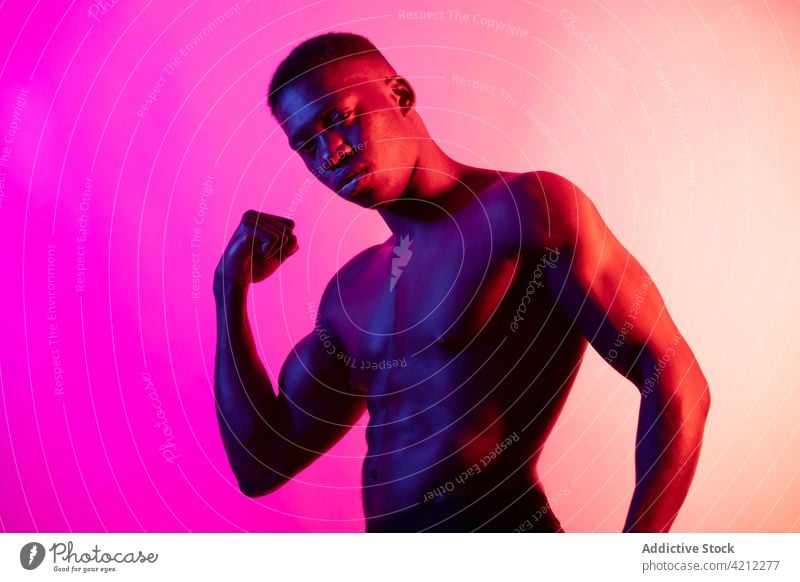 Serious shirtless African American man with fists in studio sporty strength serious muscular athlete confident fist up studio shot naked torso african american