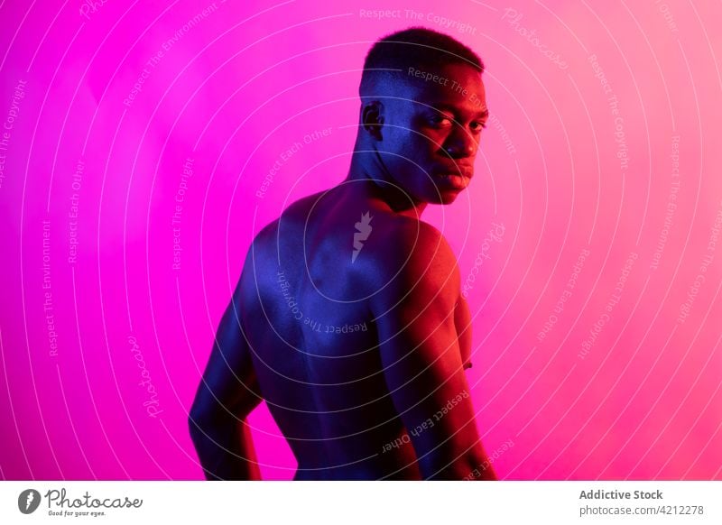 Emotionless shirtless black guy on pink background man sporty muscular serious athlete emotionless neon studio shot confident african american male young muscle
