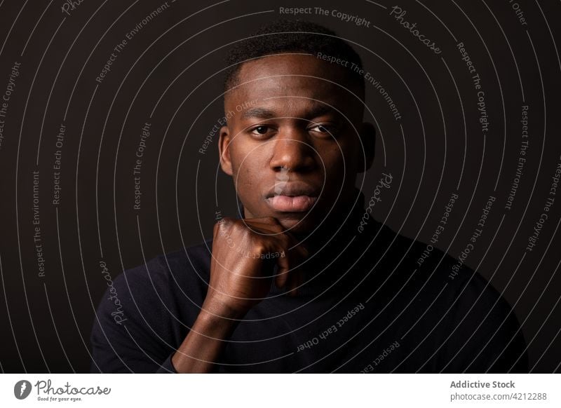 Thoughtful black man on black background portrait thoughtful studio shot emotionless alone serious hand at chin touch chin pensive african american male young