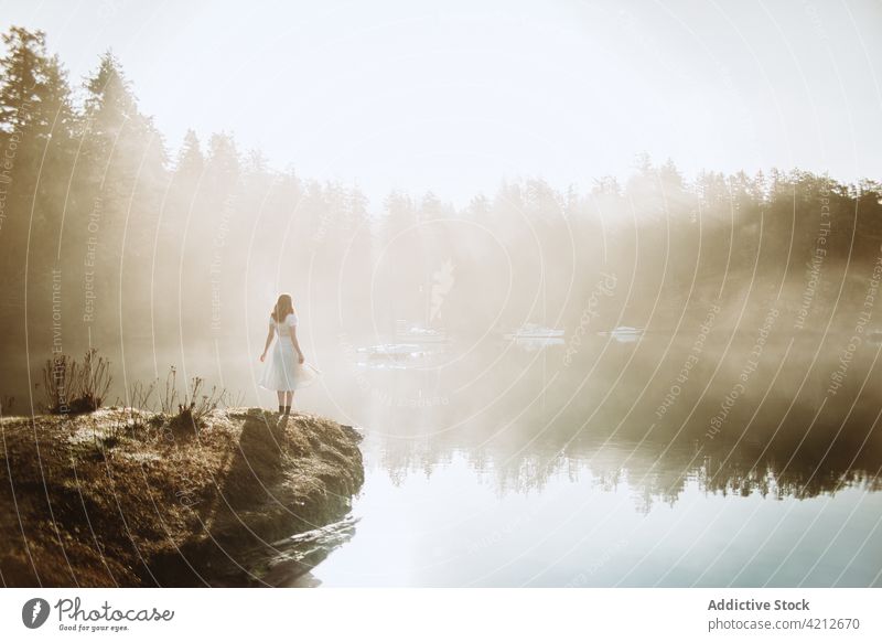 Woman standing on a rock looking at a lake on a foggy day nature woman mist water landscape people girl outdoor person female beautiful forest travel morning