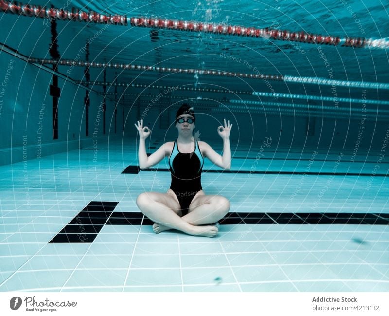 Woman sitting underwater with yoga posture sport swimmer female woman pool athlete young swimwear training blue people cap competition person lifestyle healthy
