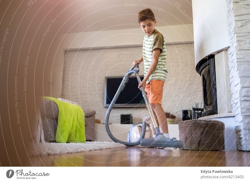 Boy vacuuming floor at home vacuum cleaner housework chores helping learning family people child son boy kid kids children lifestyle elementary offspring