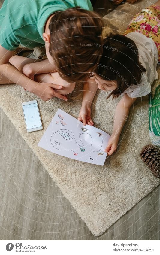 Top view of kids playing treasure hunt at home on the carpet top view unrecognizable treasure hunting game mobile compass map looking family child leisure