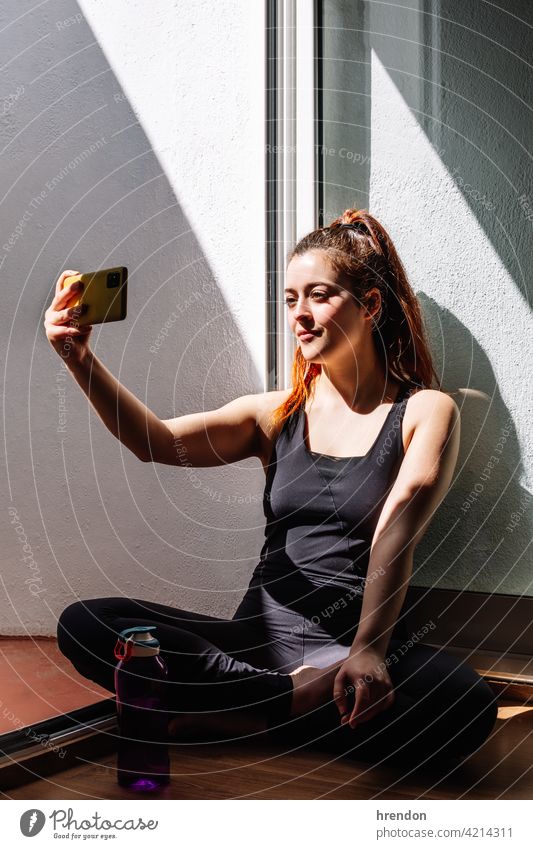 Fitness woman sitting and using mobile phone fitness room training floor smart phone living room relax gym relaxing athlete workout wellness healthy lifestyle
