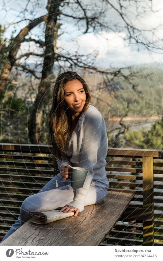 Smiling woman relaxing on terrace at sunset cup drink enjoy smile balcony house nature cheerful summer coffee tea beverage hot drink sundown happy rest glad