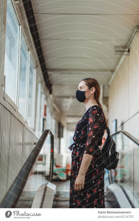woman with face mask standing on moving escalator adult attractive beautiful beauty business casual caucasian city coronavirus covid 19 entrance fashion female