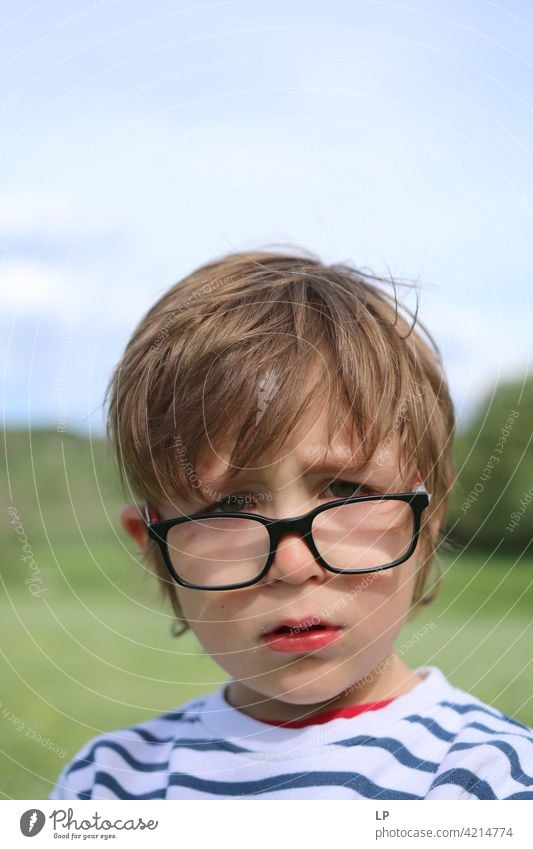 Child wearning glasses crying and looking at the camera hesitant puzzled Perplexed sceptical doubts doubtful Doubt hestitate uncertainty confusion Infancy