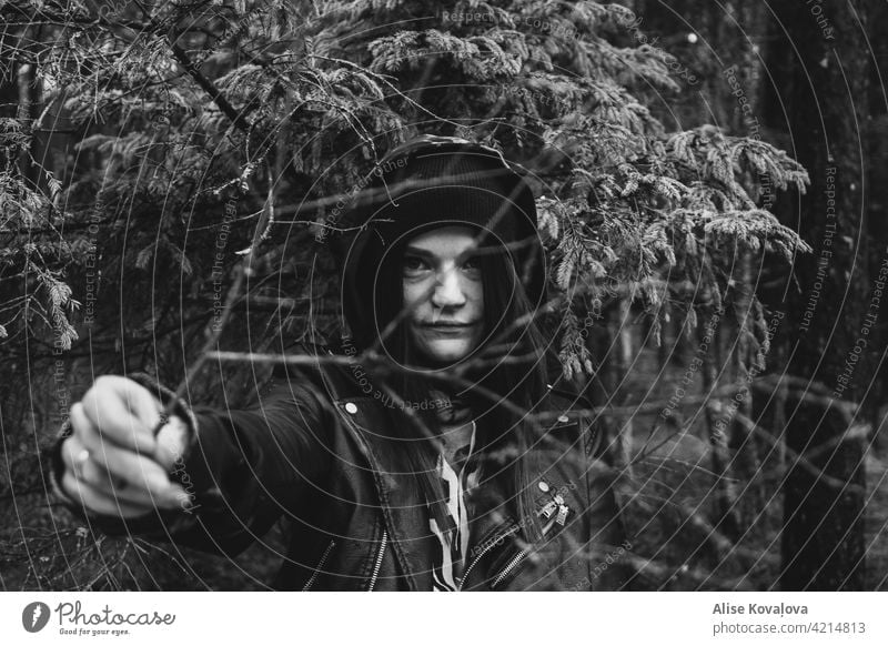 girl holding a branch in the forest Portrait woman face branches black and white in a forest Hat Leather jacket fingers arm showing showing a branch person