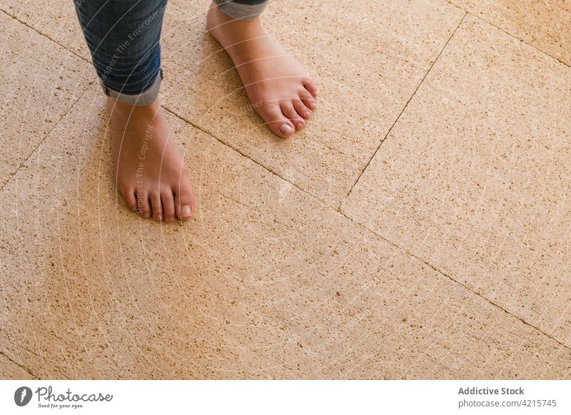 Crop barefoot person on tiled floor at home alone jeans dry rough minimal house solitude stand leg feet lonely flat minimalism geometry line straight symmetry