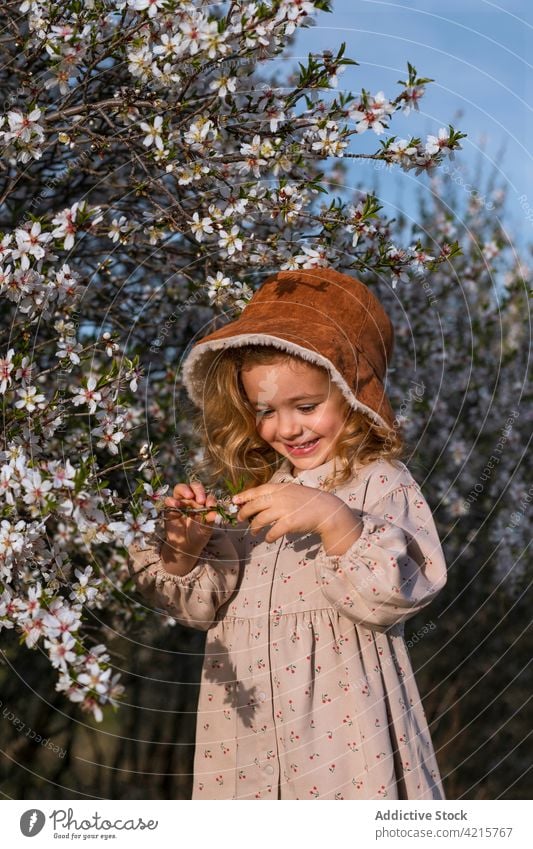 Cute little girl in blooming garden in spring flower tree portrait cheerful blossom floral dress park child cute smile kid happy childhood adorable glad joy