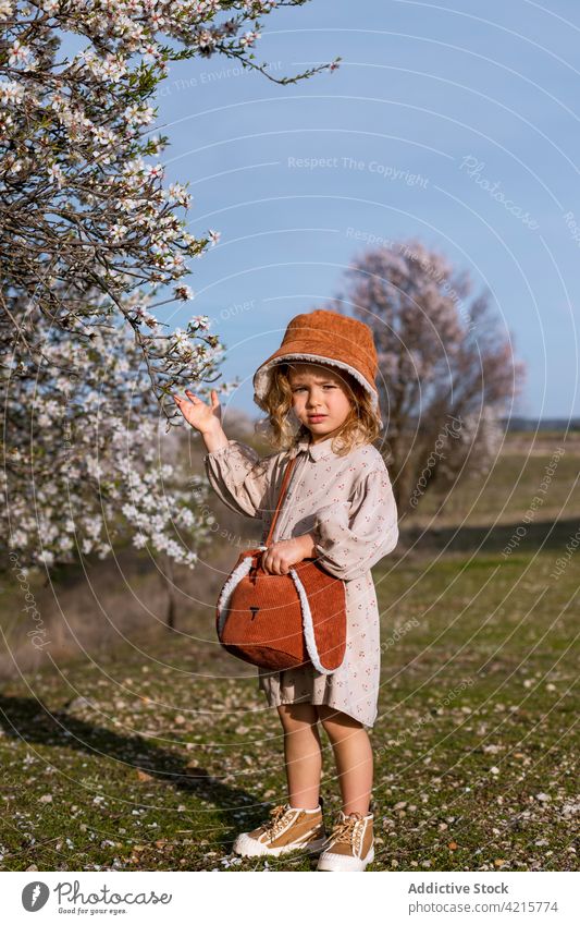 Cute girl standing in blooming spring garden tree cute child flower blossom park nature kid adorable childhood charming hat dress innocent harmony flora little
