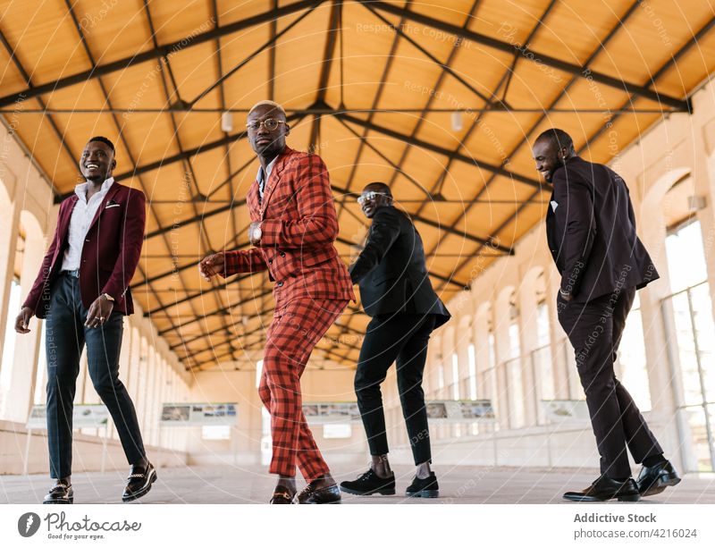 Black men in stylish suits having fun in building dance style fashion enjoy individuality cool active masculine eyeglasses afro braid show accessory demonstrate