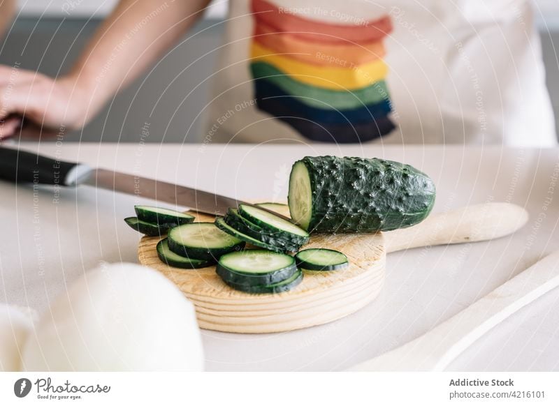 Crop lesbian woman cutting cucumber while preparing lunch at home healthy food culinary recipe vegetable wine kitchen knife onion green cutting board process