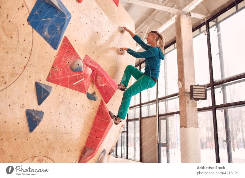 Female climber ascending wall in bouldering gym sportswoman hang training mountaineer alpinist strong female workout exercise balance grip extreme strength