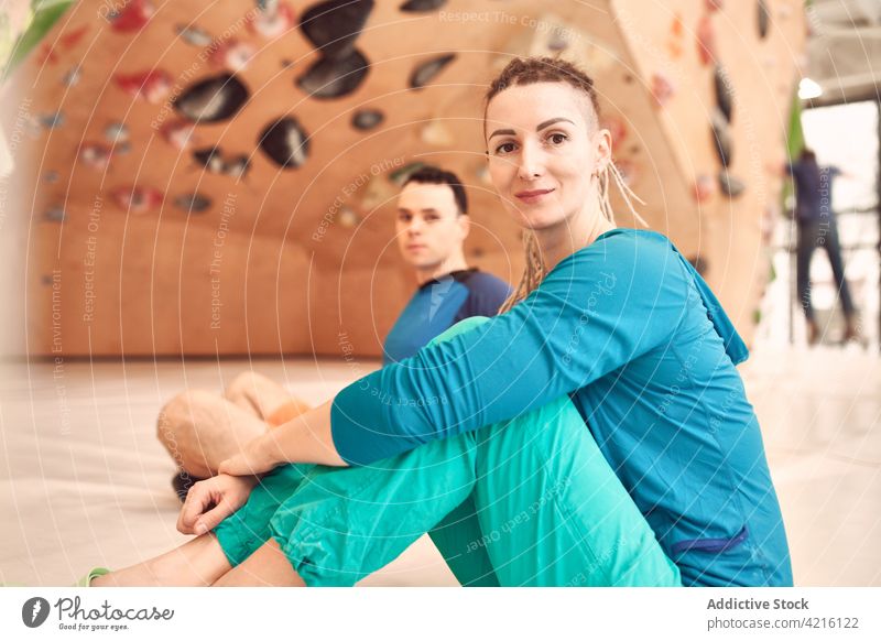 Smiling climbers in modern bouldering gym sportswoman sportsman center athlete wall artificial cheerful sit floor sportswear wellness fit strong physical