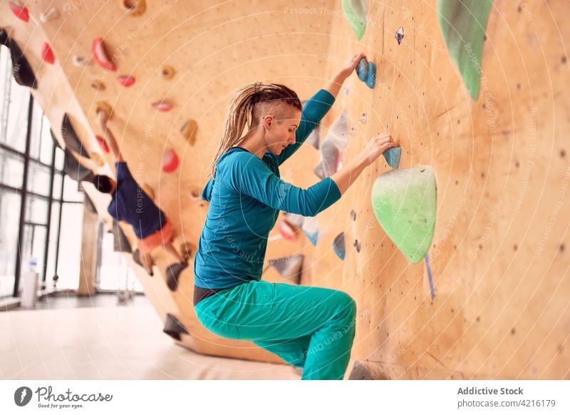 Concentrated sportsman and sportswoman practicing in climbing center wall boulder training strong climber grip exercise balance extreme mountaineer strength