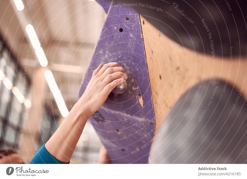 Crop woman climbing wall in bouldering center climber hang sportswoman mountaineer alpinist exercise balance female training strong clamber workout artificial