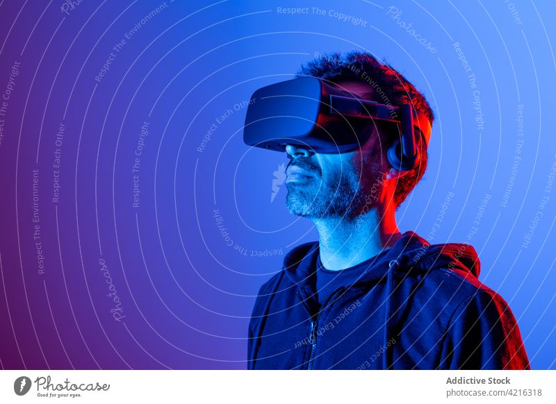 Anonymous man experiencing virtual reality in goggles headset vr explore immerse simulate technology entertainment neon using gadget masculine device modern