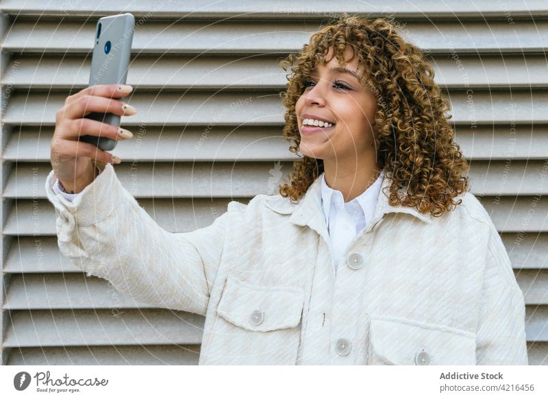 Smiling black woman taking selfie in city self portrait smartphone cheerful afro hairstyle memory moment female ethnic african american urban device mobile
