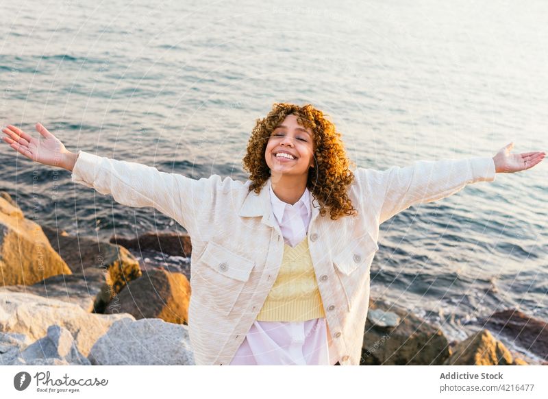 Black woman enjoying freedom at seaside seashore sunset outstretch arm carefree cheerful female ethnic black african american summer holiday nature smile