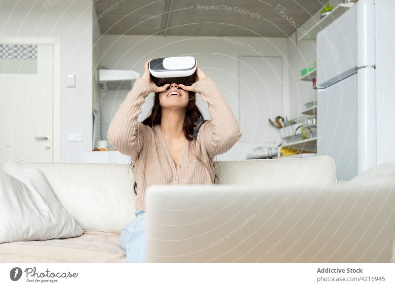 Unrecognizable smiling woman experiencing virtual reality in goggles at home experience entertainment technology immerse smile sofa using gadget device explore