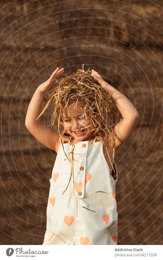 Cute girl playing with straw in field bale hay having fun countryside cheerful child childhood cute adorable kid nature overall idyllic little happy joy rural