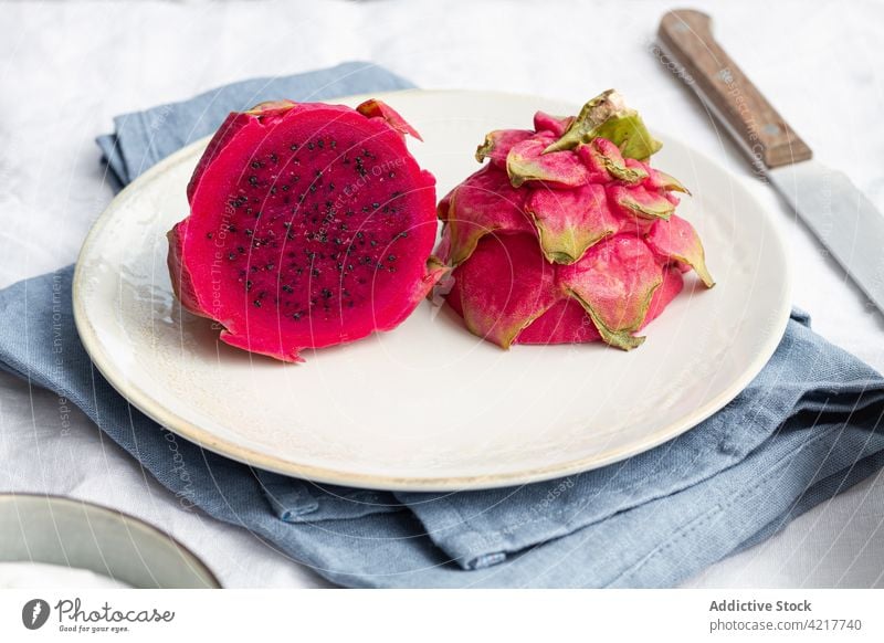Delicious cut fresh dragon fruit on plate ripe vitamin delicious sweet pulp juicy tropical exotic tasty small seed pink color cloth knife utensil natural