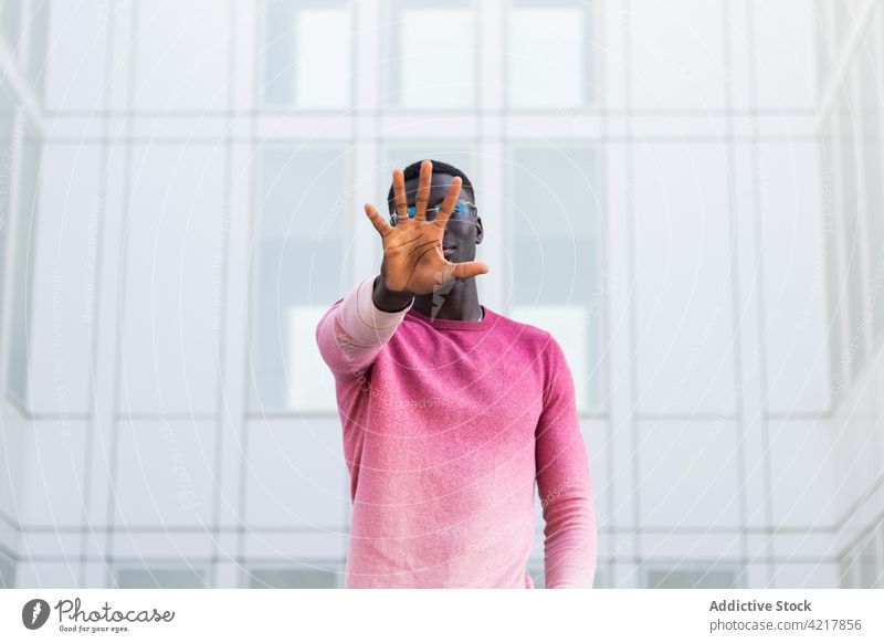 Black man covering face and showing stop gesture in city street cover face sign no hide style trendy prohibit male ethnic black african american personality