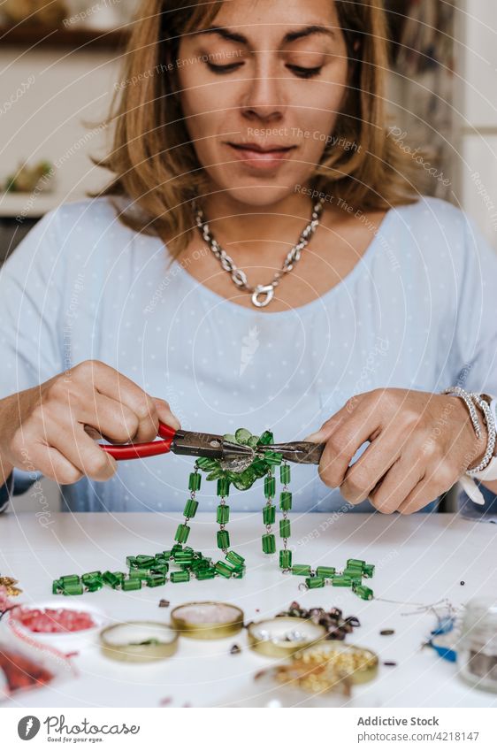 Woman making accessory with natural stones woman artisan necklace skill instrument workshop decorate adorn create female process designer bijouterie pincers