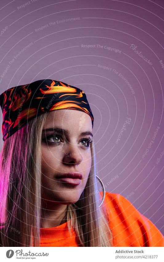 Cool woman looking away in studio cool tattoo appearance trendy outfit female individuality fashion hipster style young independent bandana headgear content