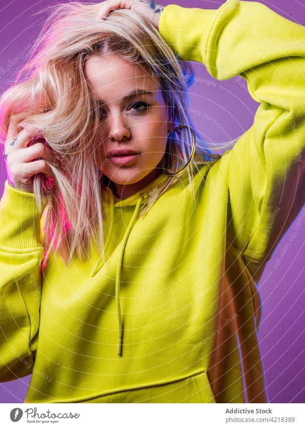 Stylish woman in studio with neon illumination hoodie light style street style outfit determine cool female vivid color glow model fashion blue confident pink