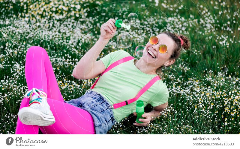 Excited woman playing with soap bubbles on lush grassland joy valley carefree excited nature outfit expressive fun bright happy cheerful glad toy colorful glade
