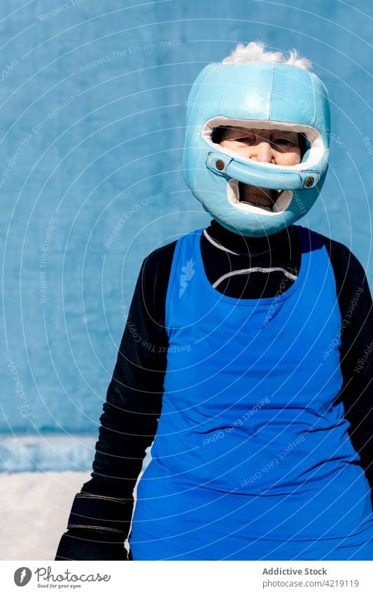 Cheerful elderly woman in boxing gloves standing with helmet senior content sport motivation endurance sporty active mature activewear carefree happy positive