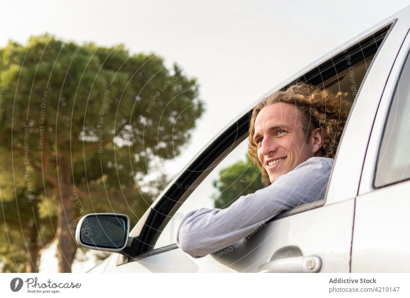 Happy man in car looking away drive hand happy nature trip smile enjoy window freedom summer travel driver male young cheerful journey lifestyle adventure