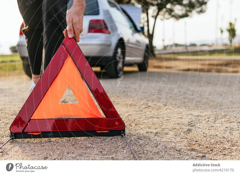 Driver putting red triangle near broken car sign emergency driver transport problem warning road vehicle automobile breakdown man accident damage safety male
