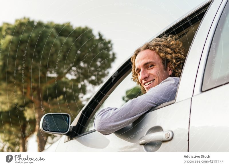 Happy man in car looking at camera drive hand happy nature trip smile enjoy window freedom summer travel driver male young cheerful journey lifestyle adventure