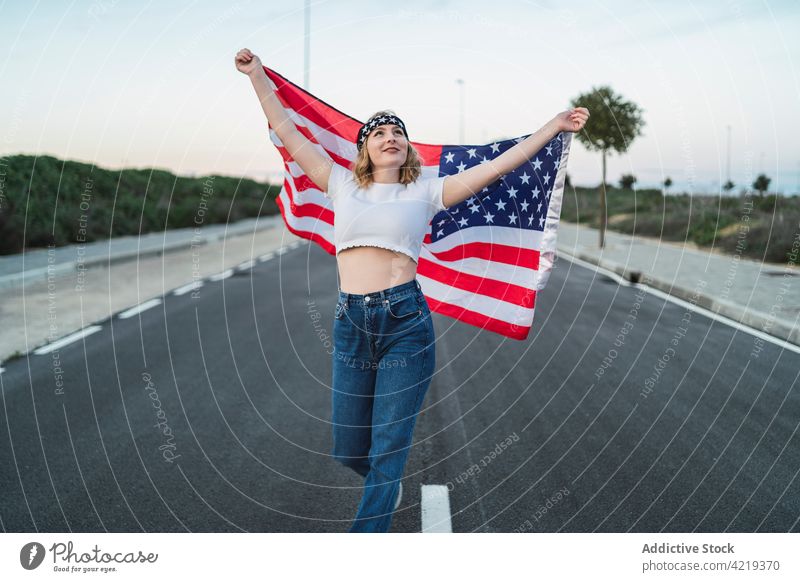 Content woman with USA flag standing on road patriot carefree content freedom national sunset symbol female american usa united states independent smile