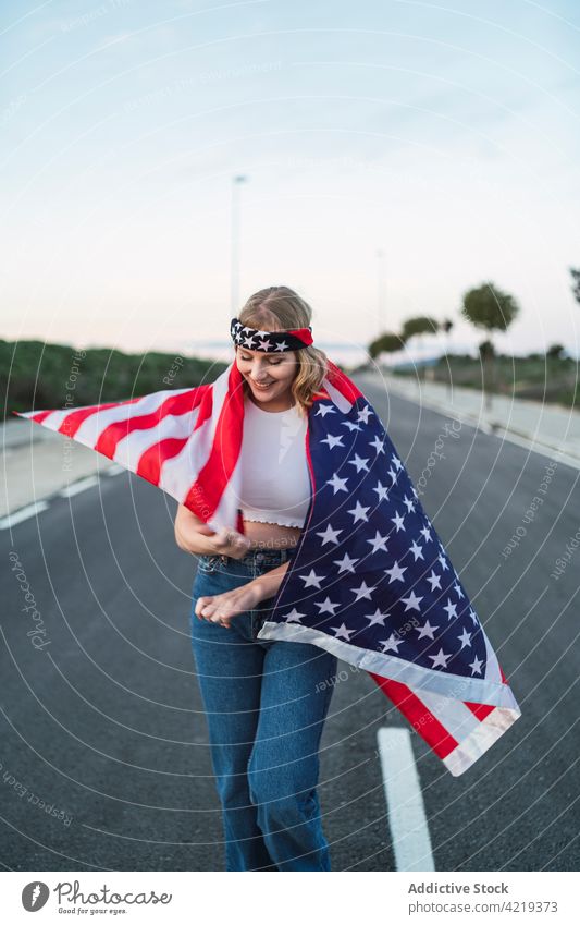 Content woman with USA flag standing on road patriot carefree content freedom national sunset symbol female american usa wrapped united states independent smile