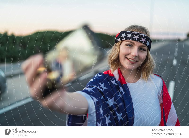 Woman with American flag taking selfie on smartphone woman self portrait photo national patriot independent country female american usa united states 4th july
