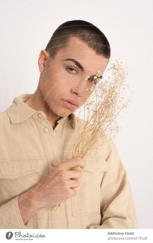 Stylish man with dried plants in studio androgynous model style fashion feminine bunch male appearance individuality trendy outfit vogue personality tender