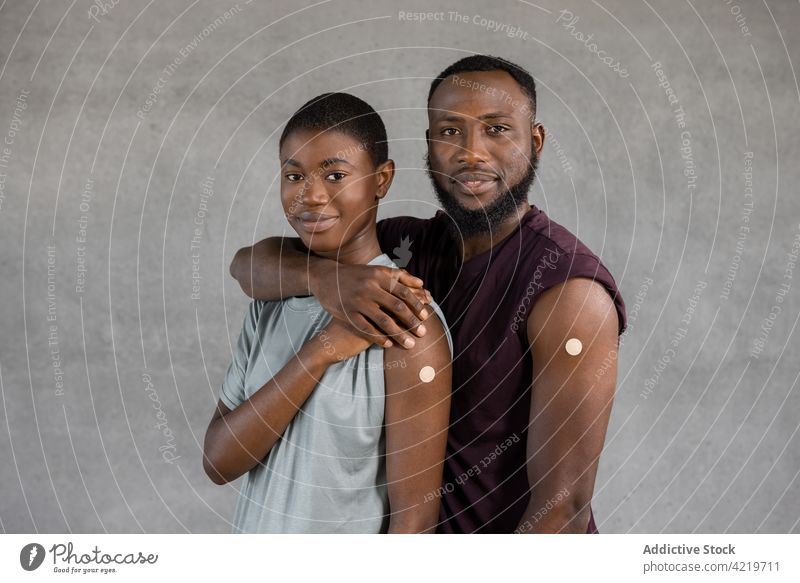 Ethnic couple with adhesive bandage plaster on arm after getting the vaccination vaccine smile african american ethnic female embrace happy strip black woman