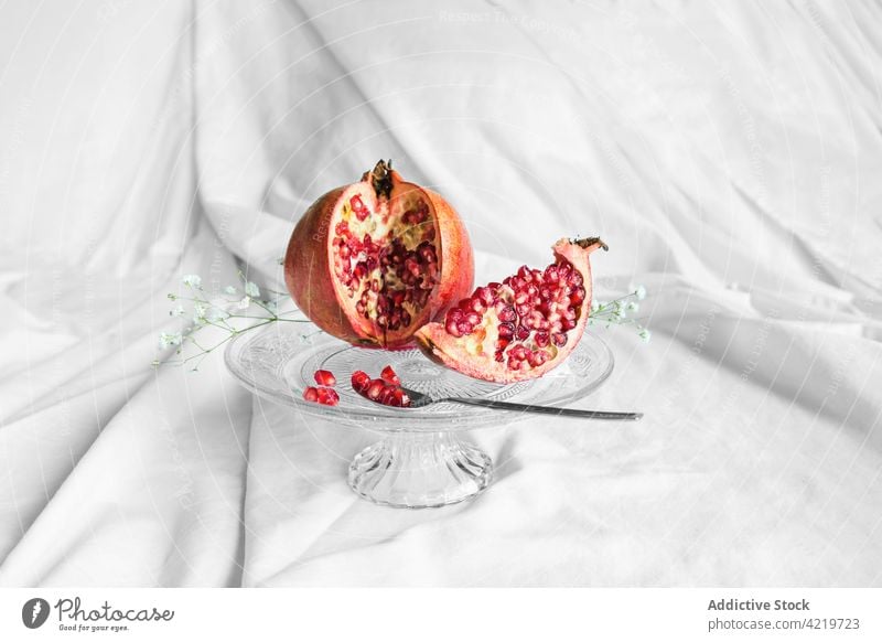 Delicious cut pomegranate on stand with spoon fruit seed natural vitamin fresh sprig fabric crumpled flower organic delicious ripe aroma yummy bloom bright