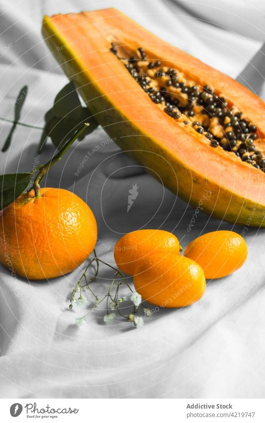 Cut papaya between mandarins and kumquats on creased fabric tangerine fruit tropical natural fresh vitamin leaf pawpaw cut half seed ripe juicy cumquat exotic