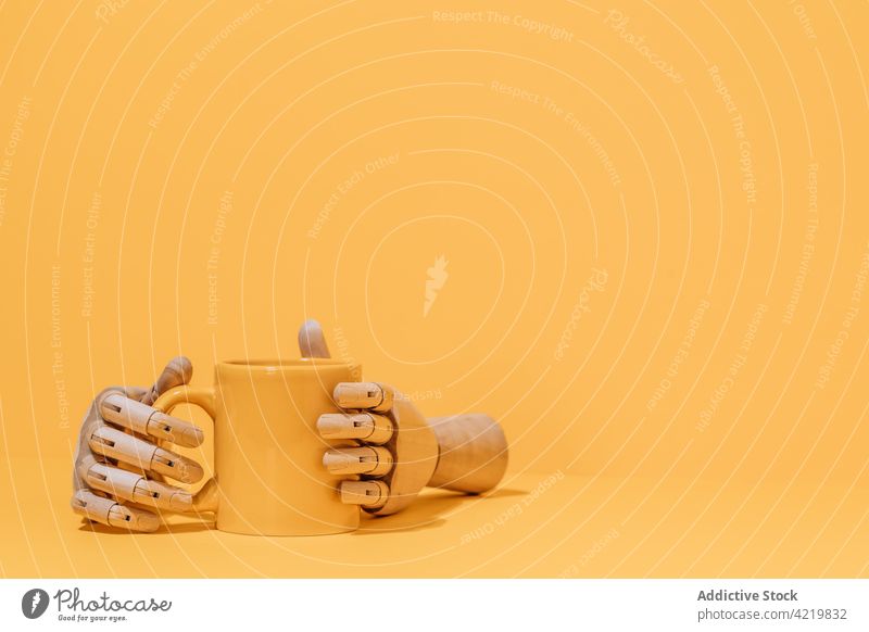 Wooden hand with coffee cup on yellow background wooden concept mug studio design beverage creative minimal object simple utensil color style tea breakfast