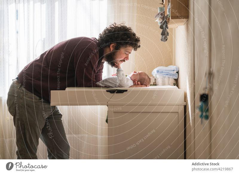 Father interacting with newborn baby at home father fatherhood innocent babyhood lean forward table man together parent dad domestic idyllic harmony casual