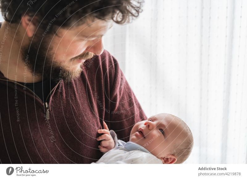 Father embracing yawning baby in plaid at home father embrace fatherhood babyhood happy infant attentive portrait man fondness dad delight smile together