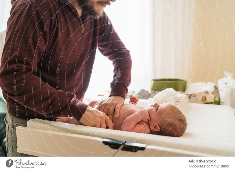 Crop father changing diaper of newborn baby at home man put on infant dad fatherhood domestic sweet table unshaven change love babyhood male parenthood idyllic