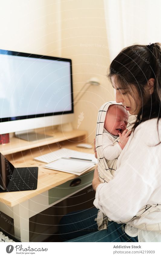 Mom cuddling newborn baby at desk in house mother cuddle babyhood motherhood love innocent tender home woman mom carrier table infant together charming ornament